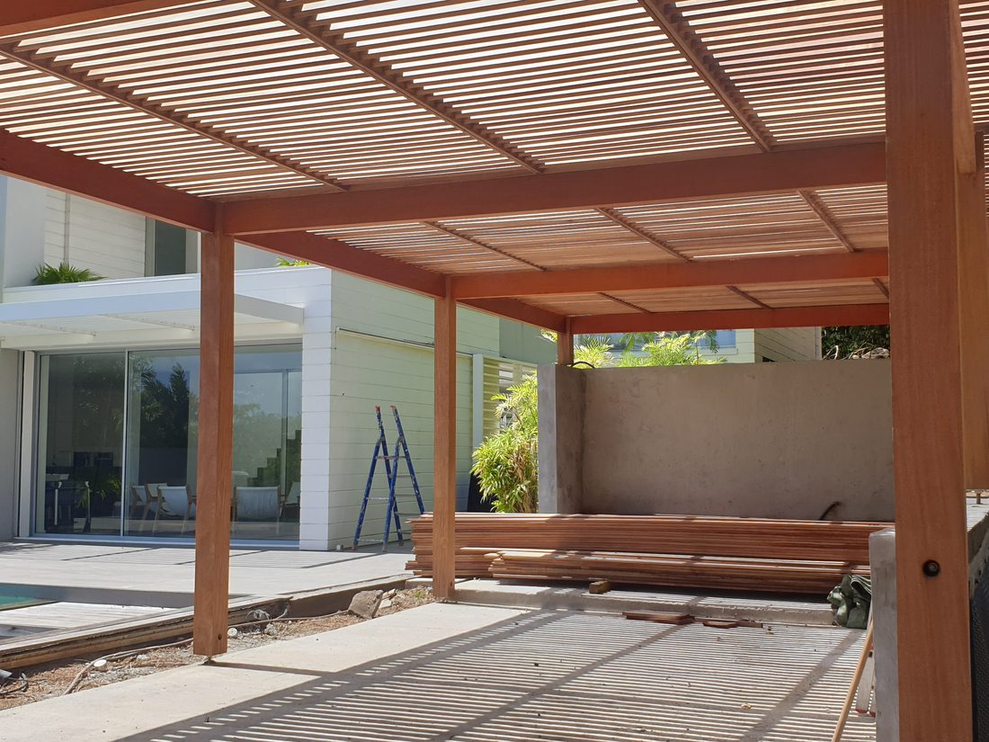 Terrasse avec pergola en bois au bord d’une piscine, réalisée par Topconstruck